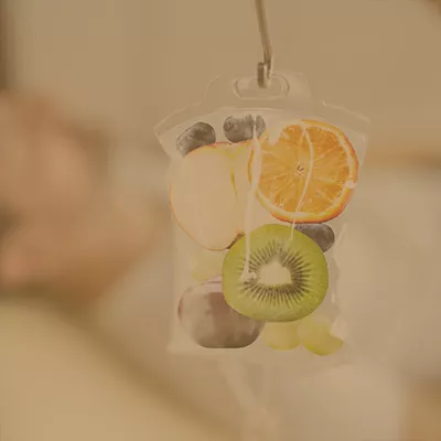 IV bag containing assorted fresh fruits including kiwi, orange, apple slices and berries